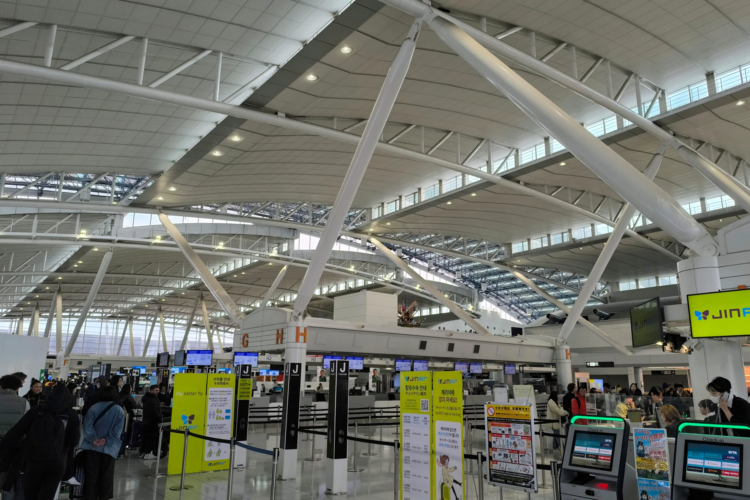福岡機場國際線出發大廳,畫面可見航空公司報到櫃檯與自助報到設備