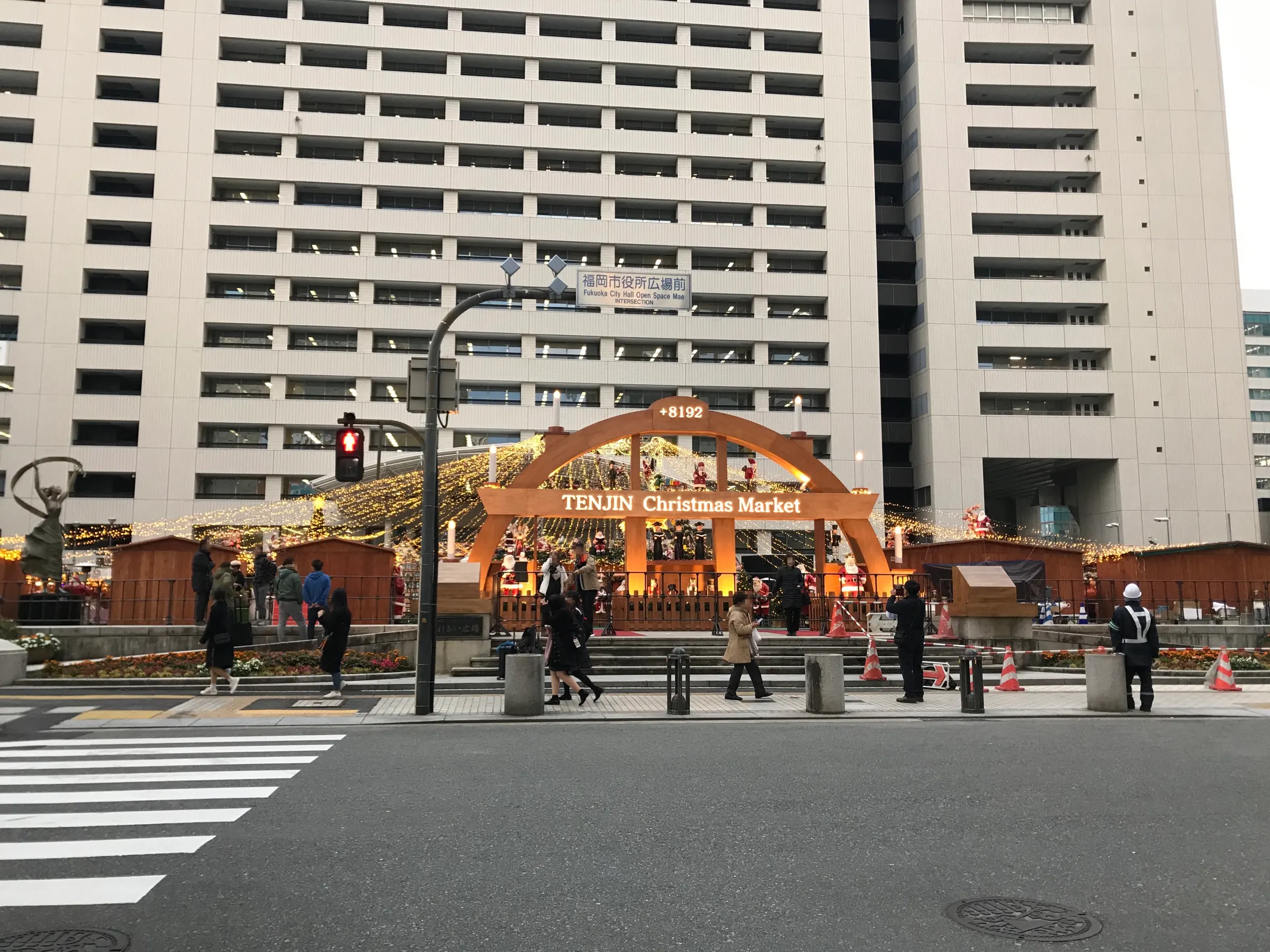 福岡市役所西側廣場的聖誕市集拱門和木造攤位，後方是市役所大樓