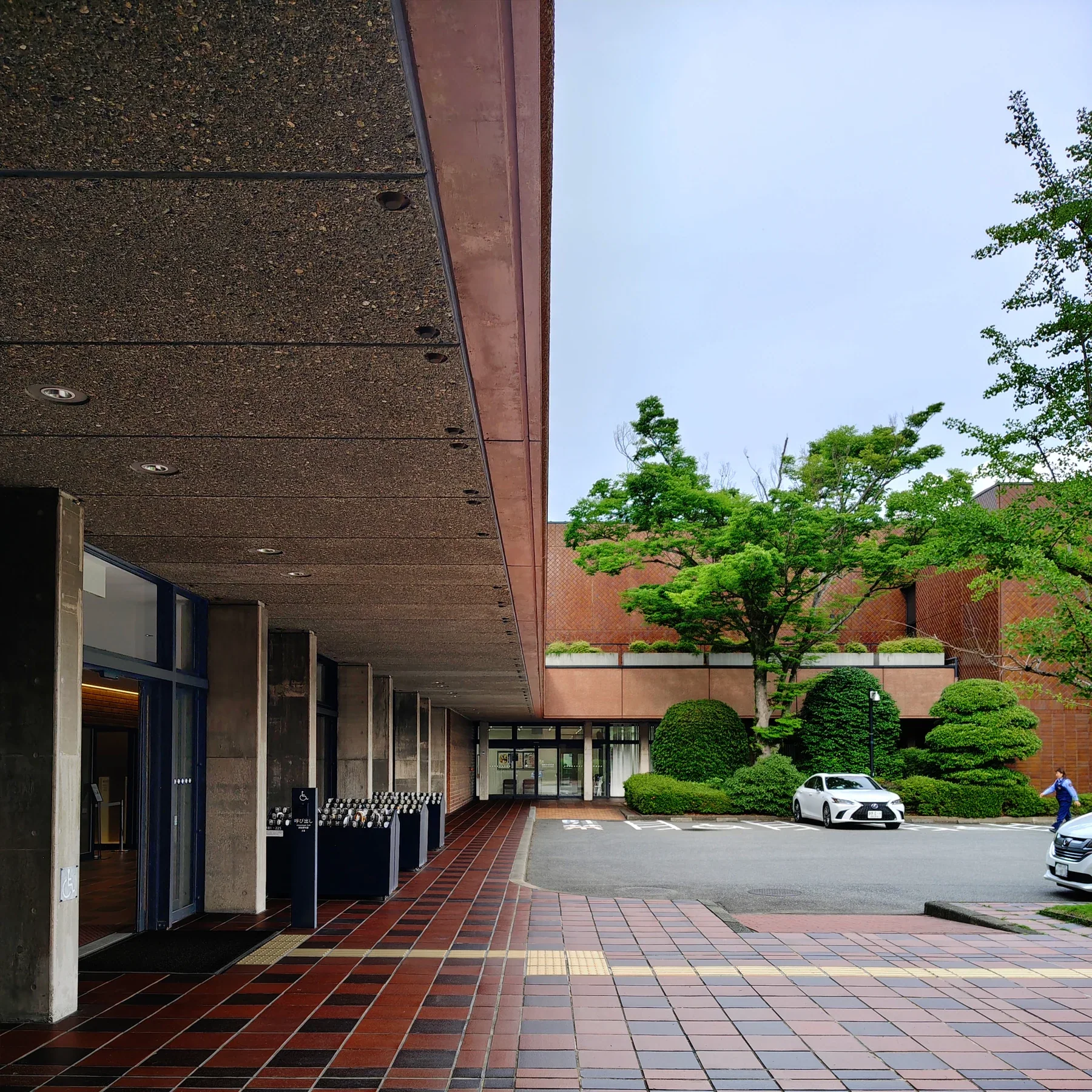 福岡市美術館南側入口前的磚紅色鋪面、入口雨棚與館舍外觀