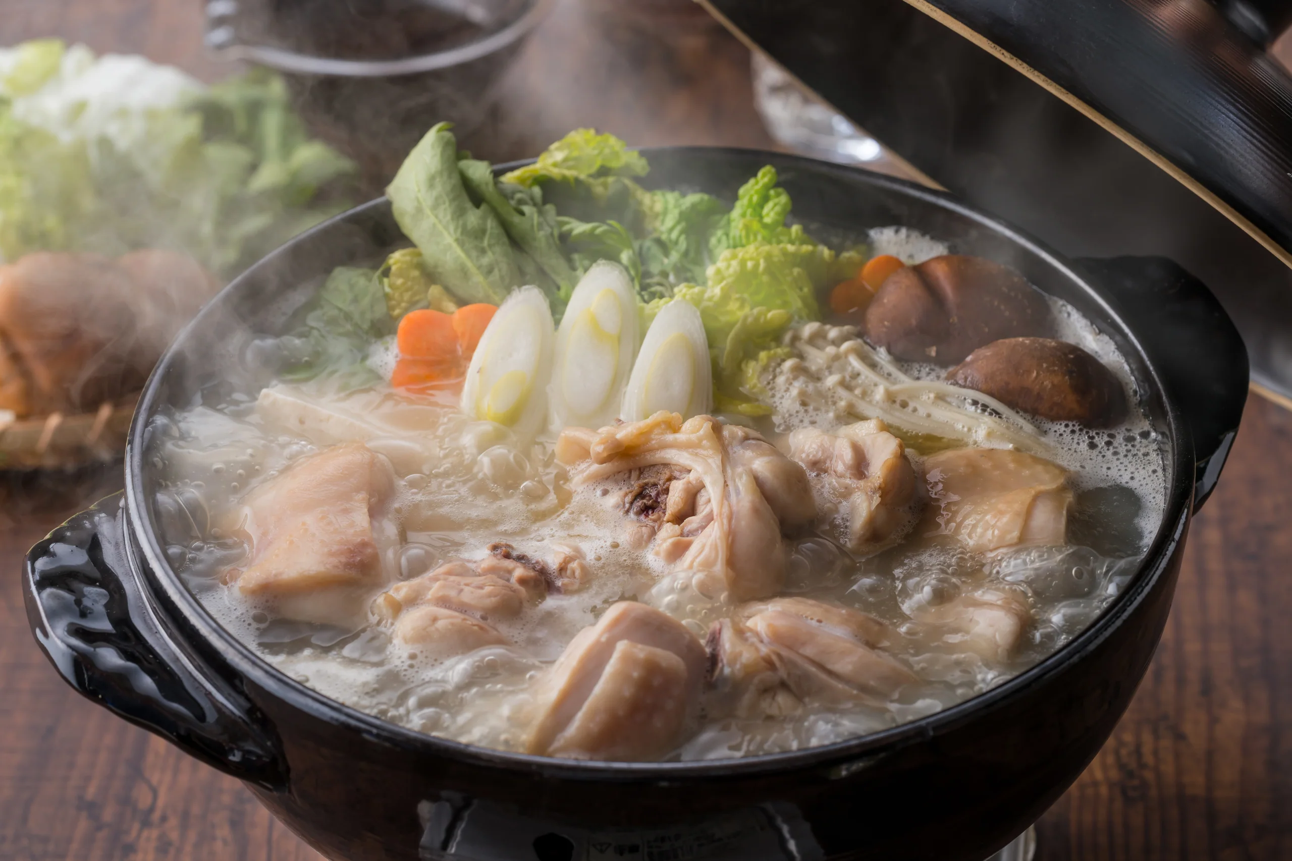 福岡水炊鍋冒出蒸氣，雞肉與蔬菜正在鍋中燉煮
