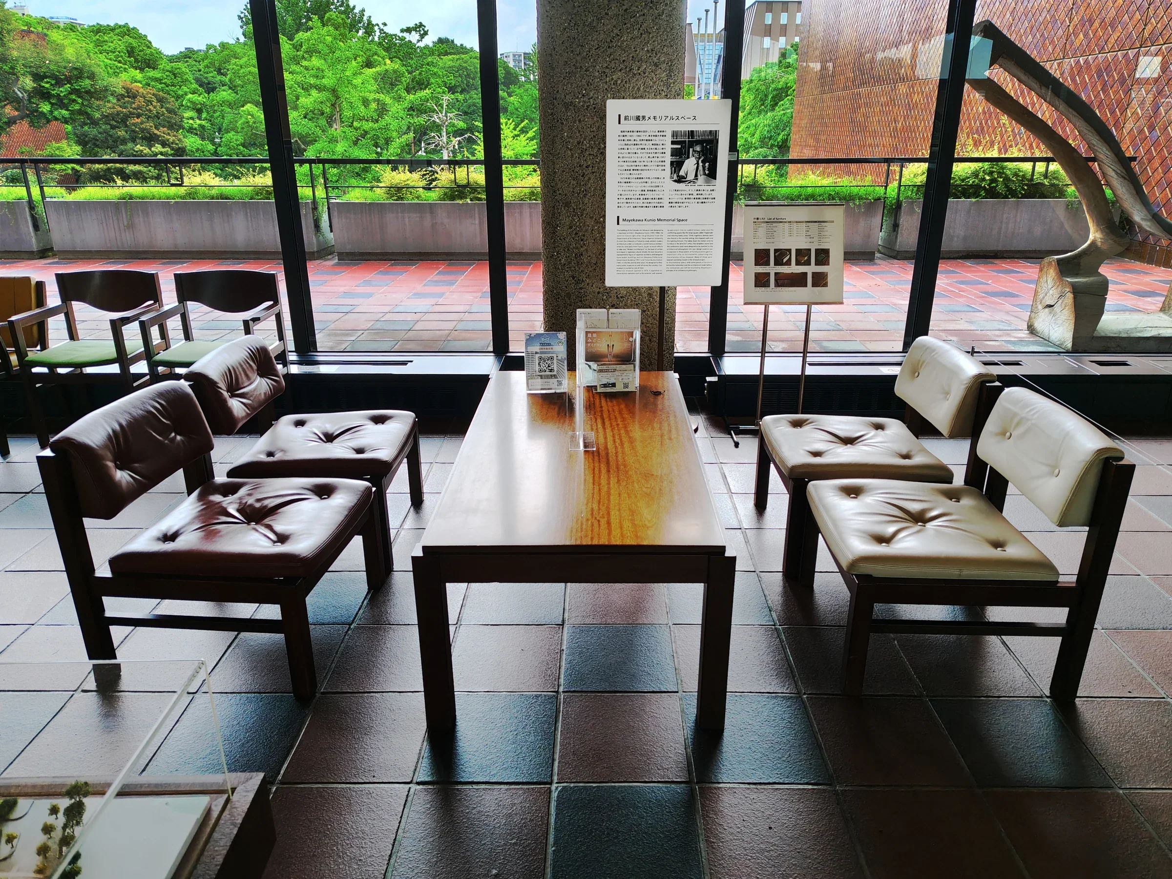 福岡市美術館大廳的座椅與長桌,落地窗外是綠樹和館舍外牆