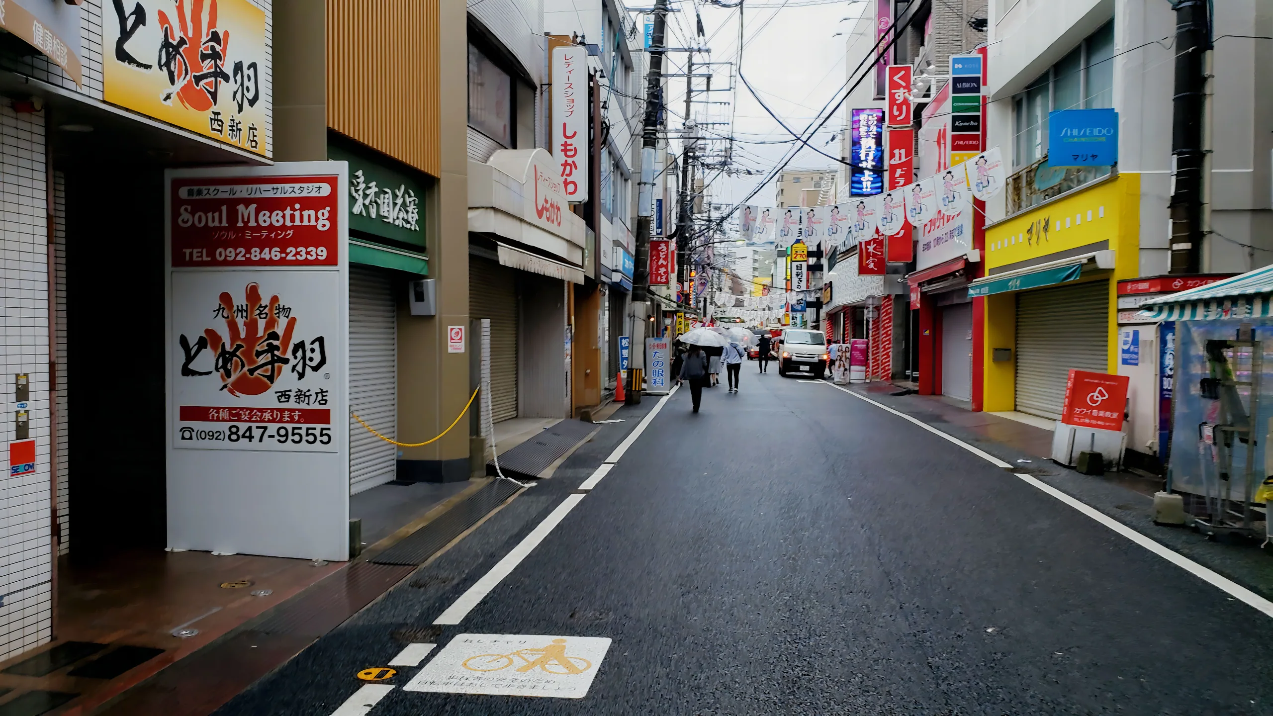 雨天的福岡市商店街街景,行人沿濕潤路面行走