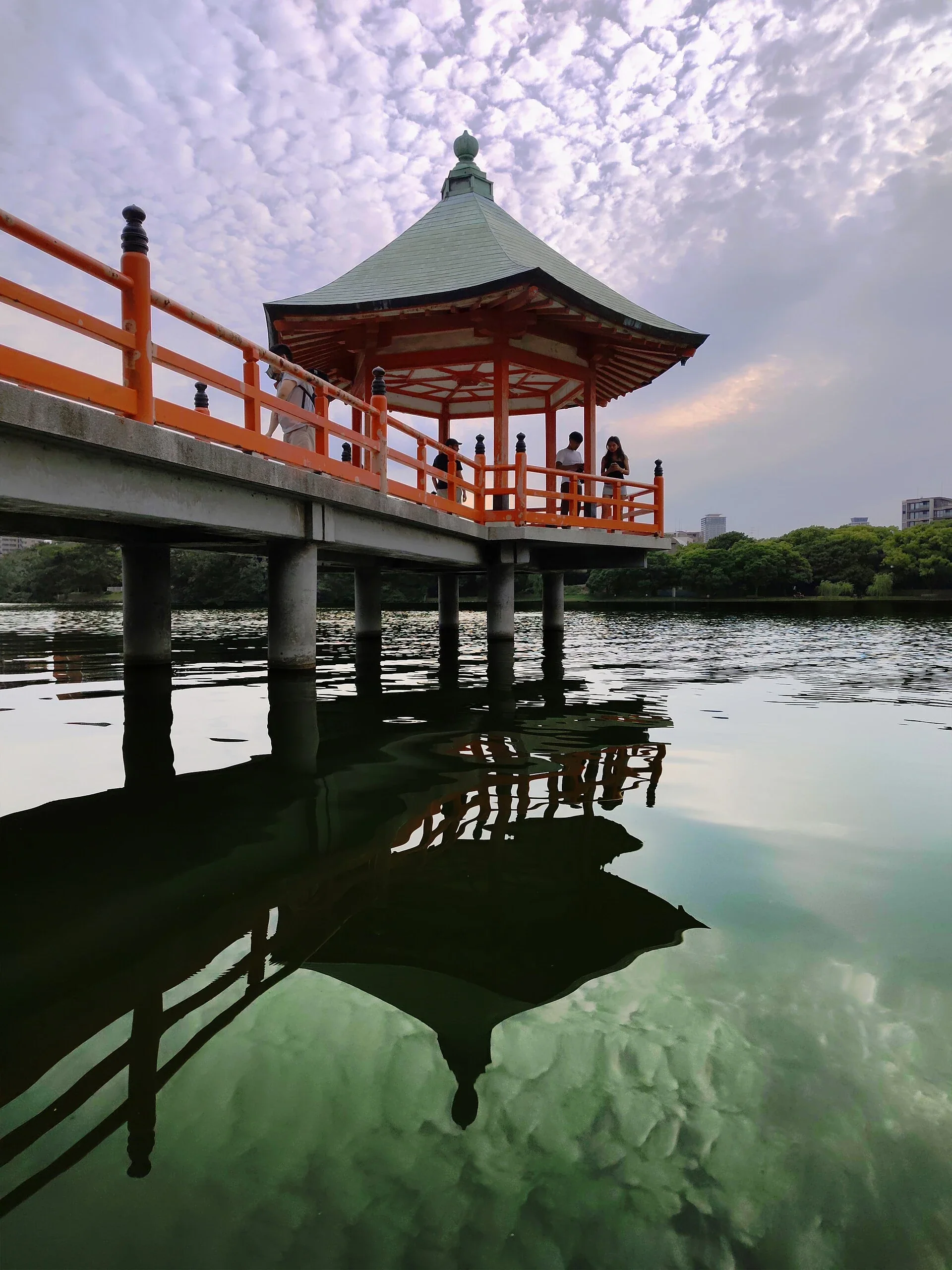 大濠公園北側浮見堂與湖面倒影，遠處可見園內樹木和福岡市區