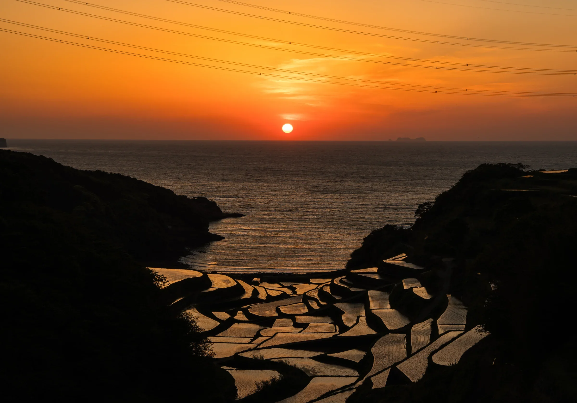 佐賀縣玄海町浜野浦梯田沿海層層延伸,遠方海灣映著晚霞