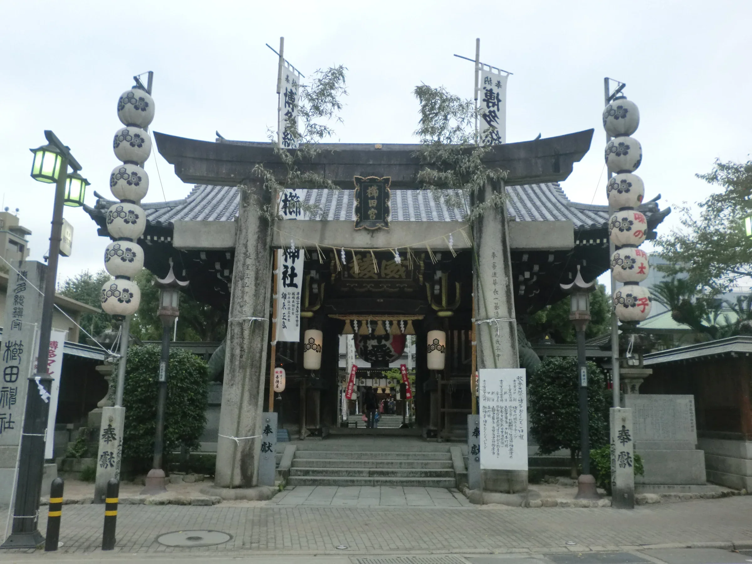 博多おくんち當日的櫛田神社,鳥居前掛有燈籠與祭典告示