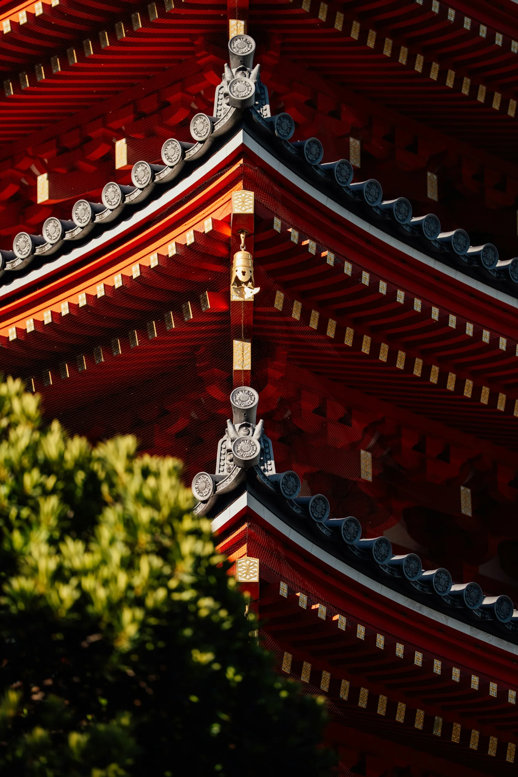 東長寺紅色瓦屋簷與金色裝飾細節,前景帶有境內樹葉