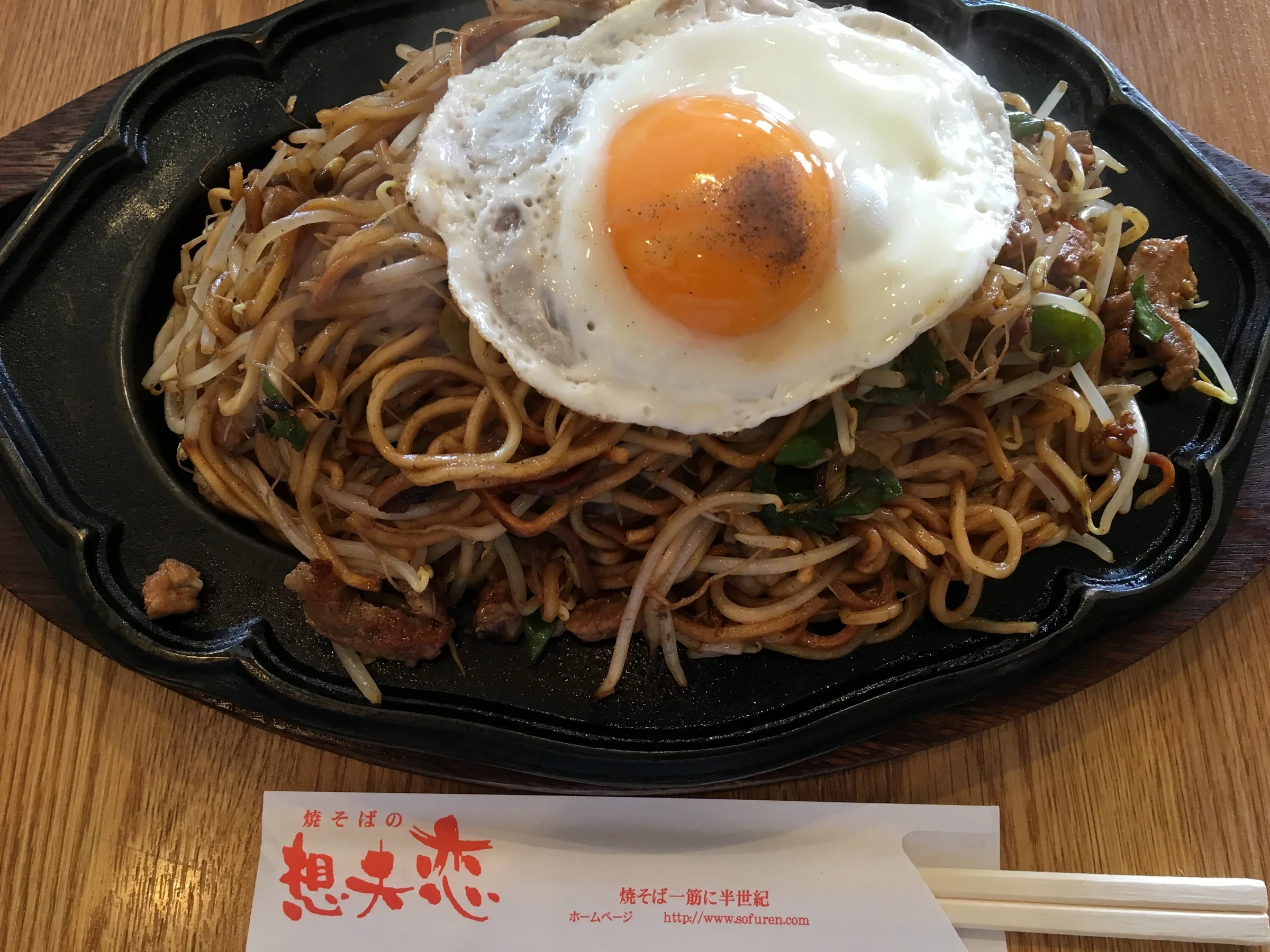 想夫戀日田燒そば盛在鐵板盤上,配有豆芽、豬肉和目玉燒