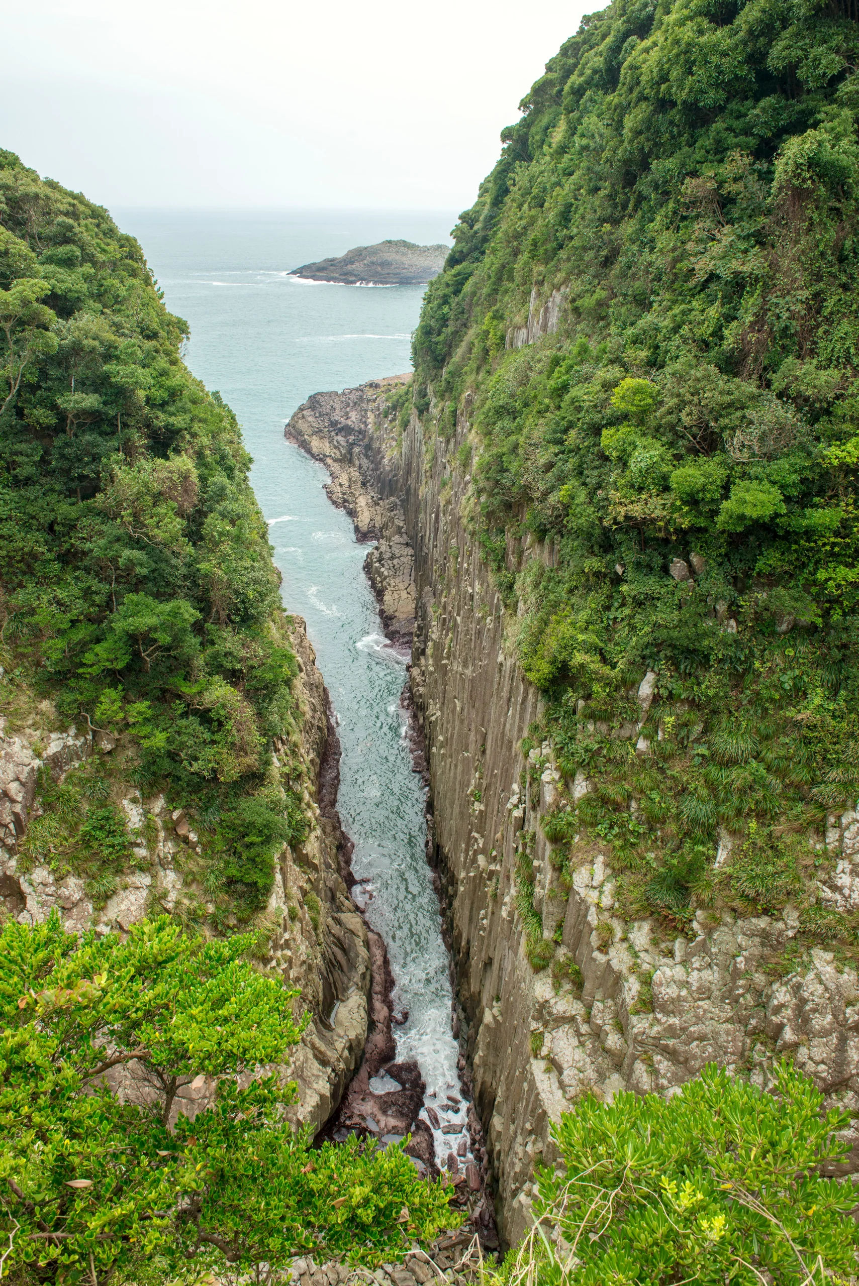 馬ヶ背海蝕峽的柱狀節理沿著兩側岩壁直落海面,崖頂覆著綠色植被