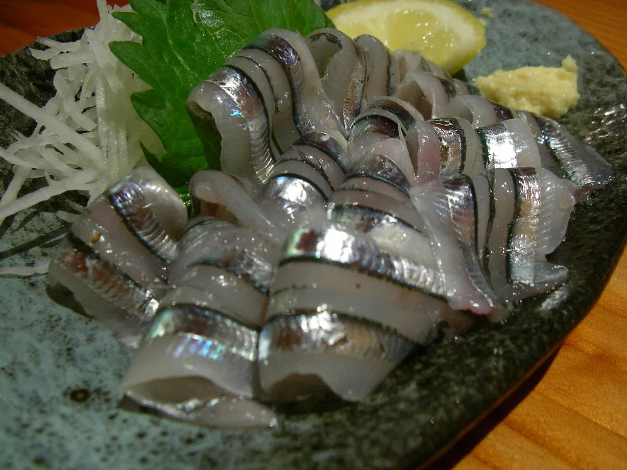 鹿兒島天文館居酒屋供應的きびなご刺身,銀白小魚排成菊花形,旁配藥味與檸檬