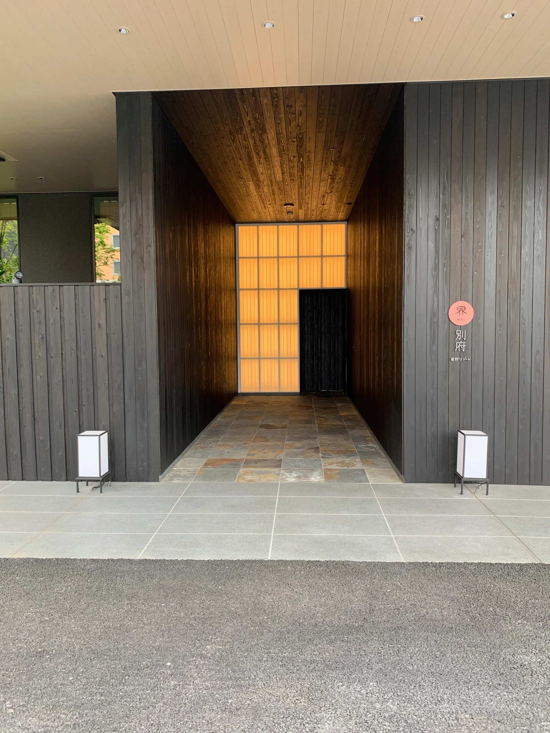 界別府入口門扉與旅館標示，木格柵後可見庭園