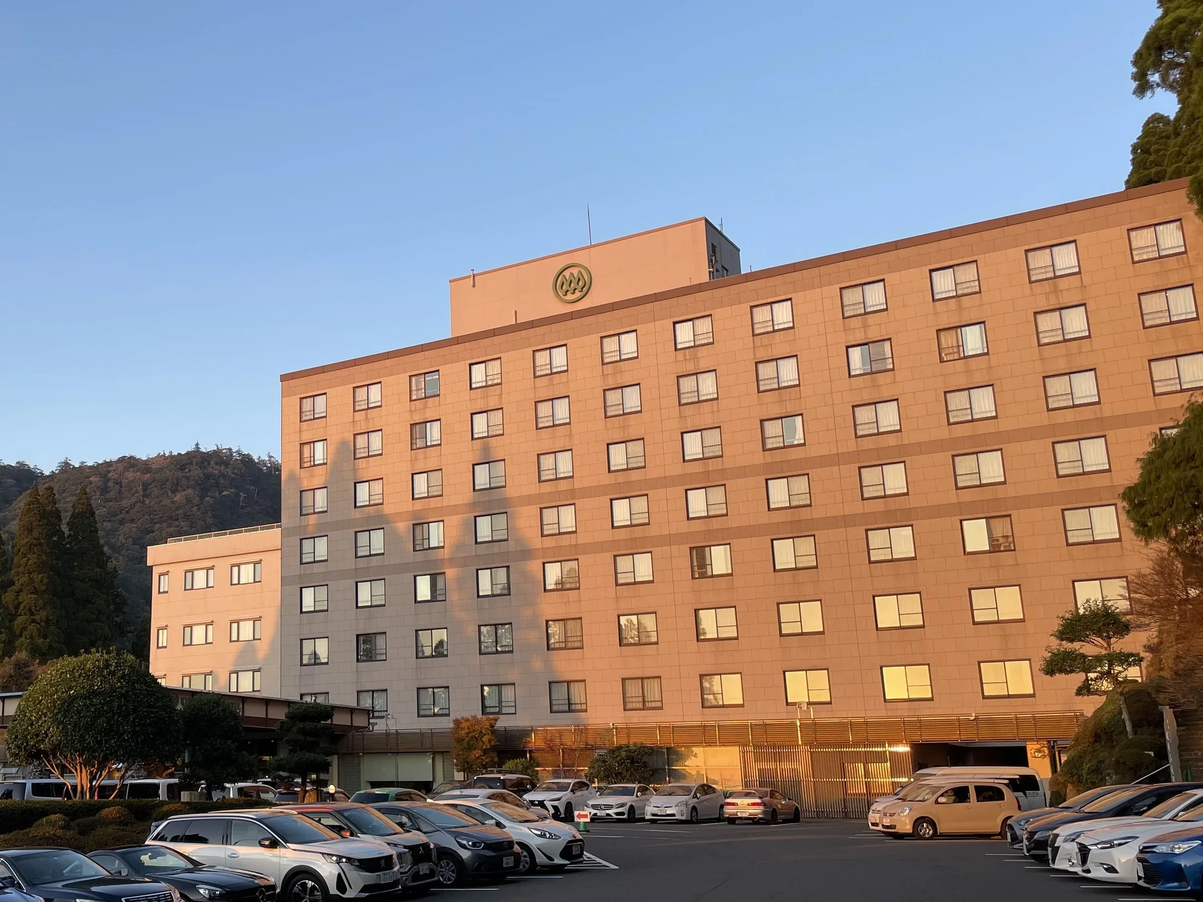 霧島酒店多層客房外牆與前方停車場,背景是霧島山林