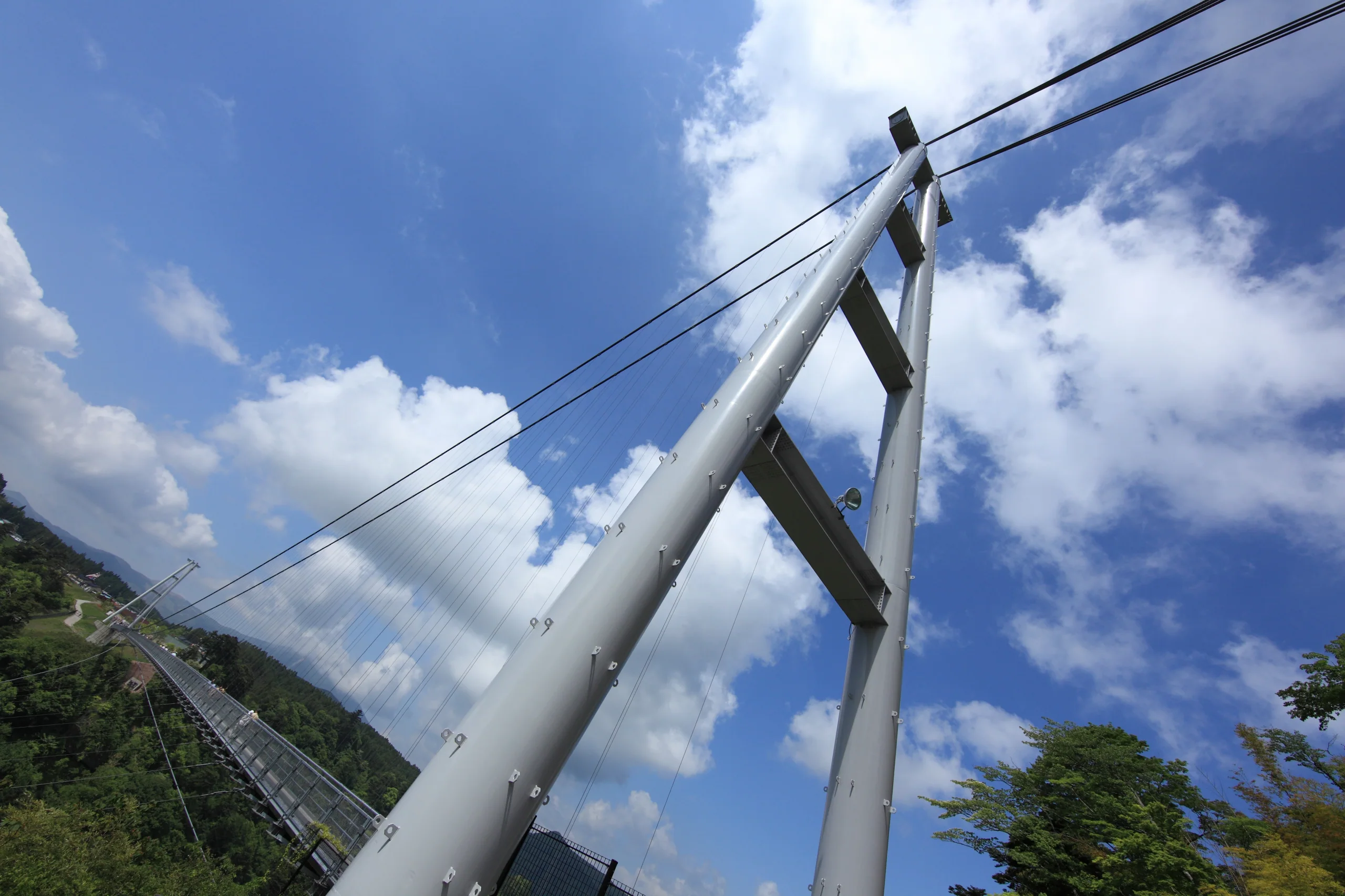 九重夢大吊橋白色主塔與鋼索由橋面仰望,遠處是九重町山谷