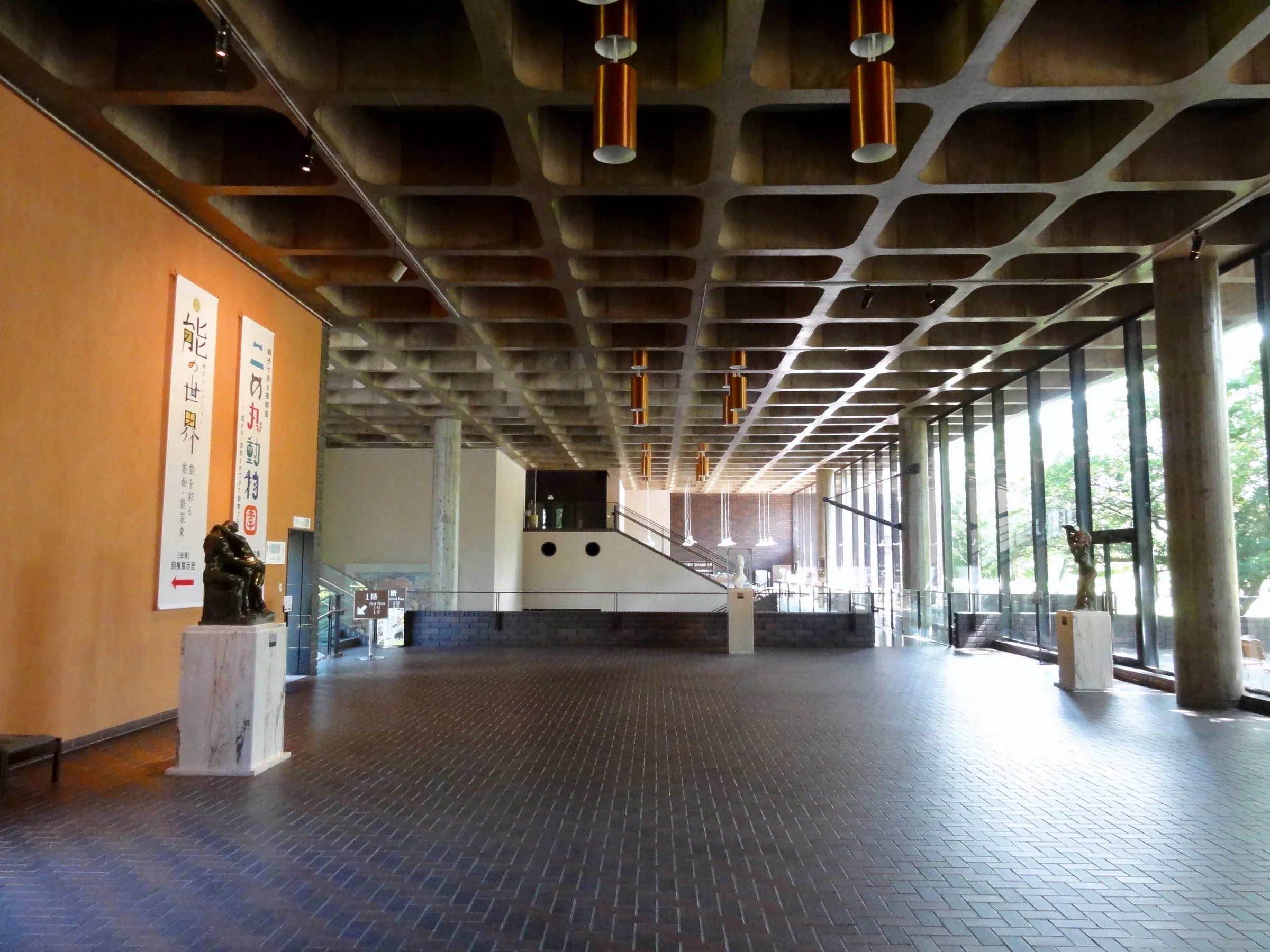 2015年7月熊本縣立美術館本館大廳的混凝土柱、格狀天花與窗邊公共空間，非2026佛像特展展場