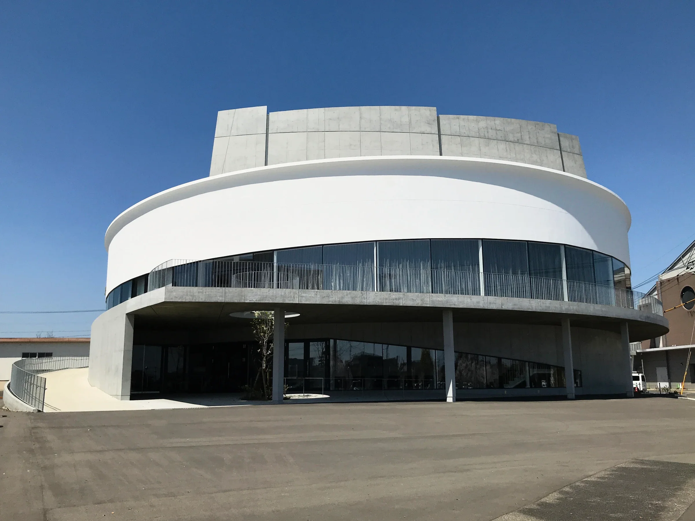鹿島市民文化會館SAKURAS的另一側外觀，弧形白色建築面向入口廣場