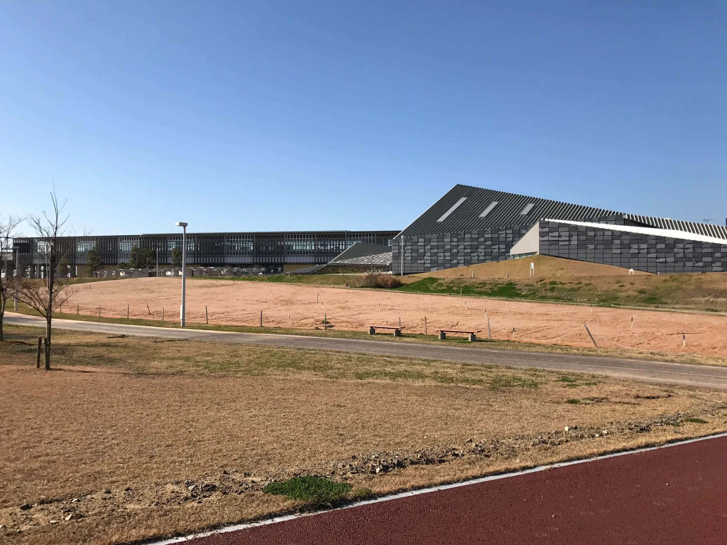 從東側公園步道望向九州藝文館屋頂與後方筑後船小屋站，步道旁有長椅