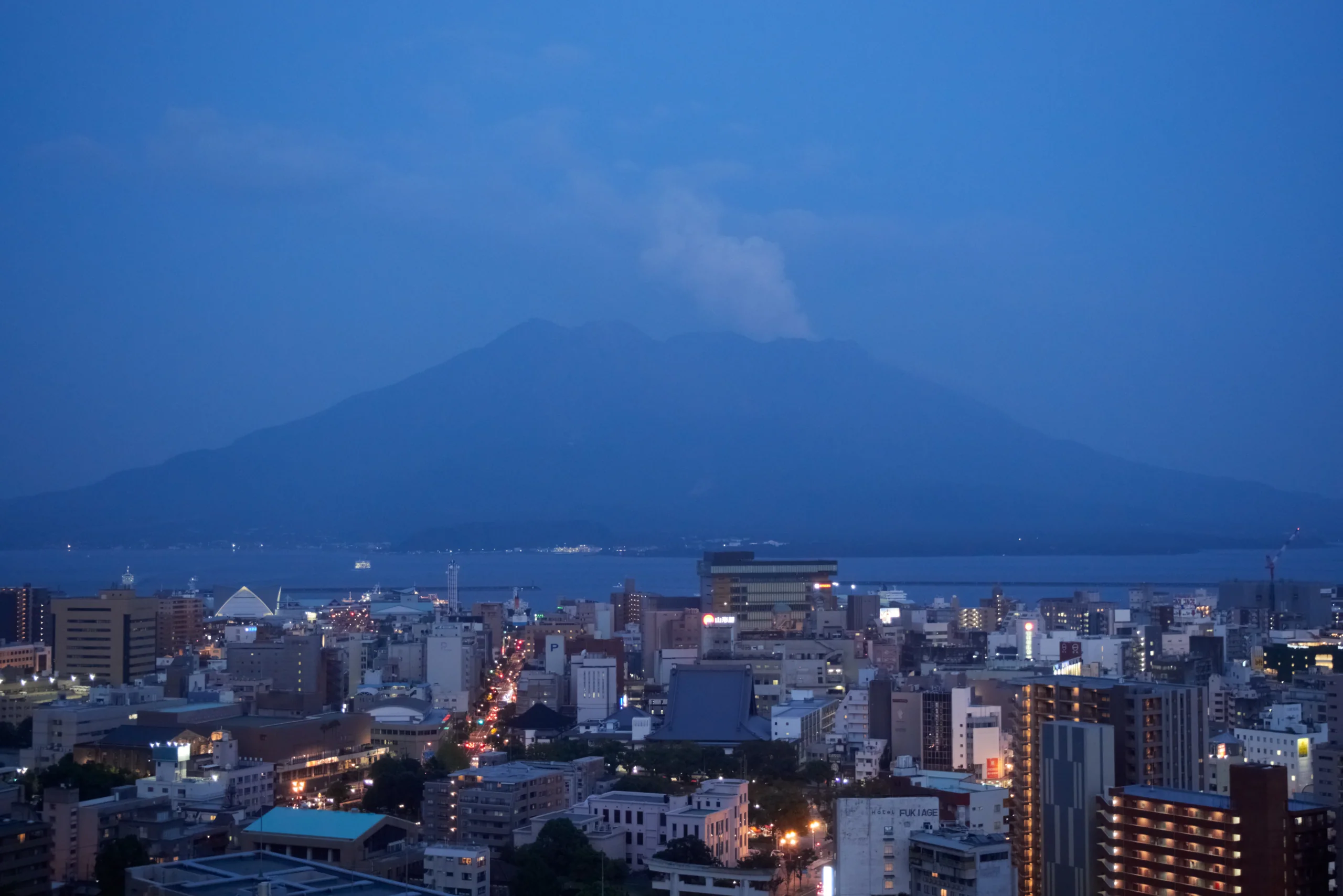 黃昏時從鹿兒島市區望向錦江灣與櫻島,遠方火山輪廓被暮色和雲氣遮住