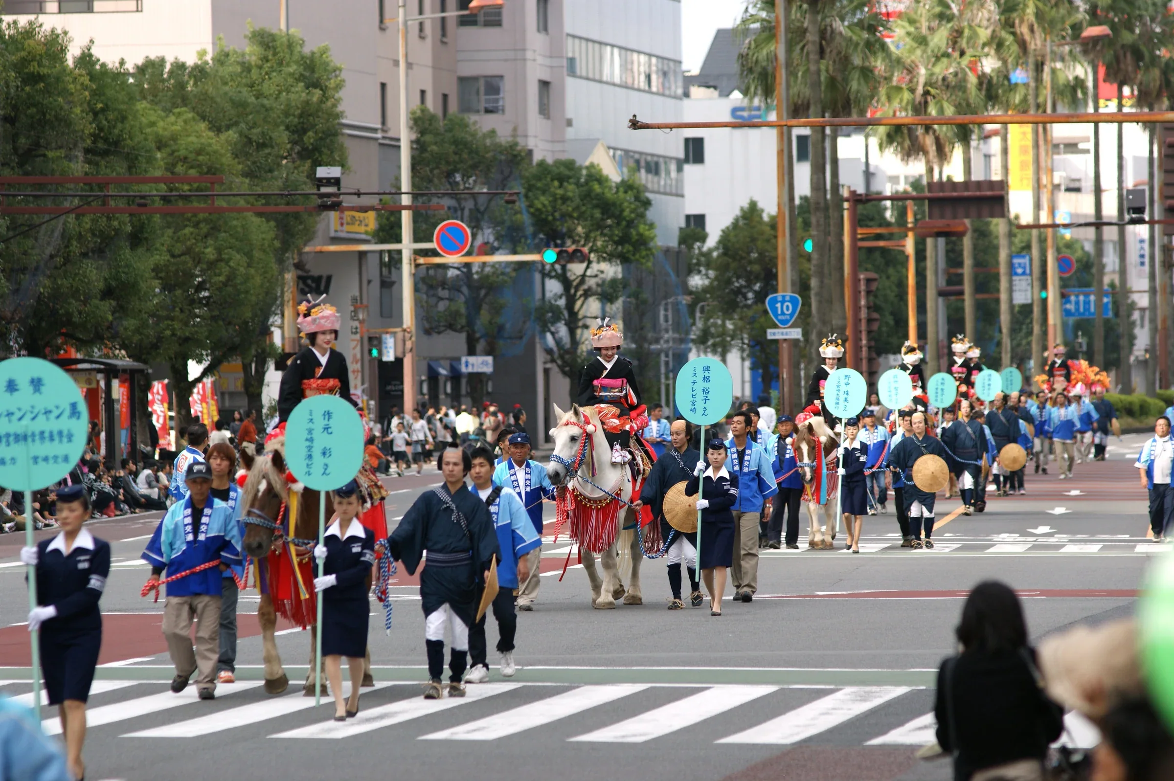 宮崎神宮大祭御神幸行列沿市中心道路前進,隊伍中有騎馬隊列與穿傳統服飾的參加者