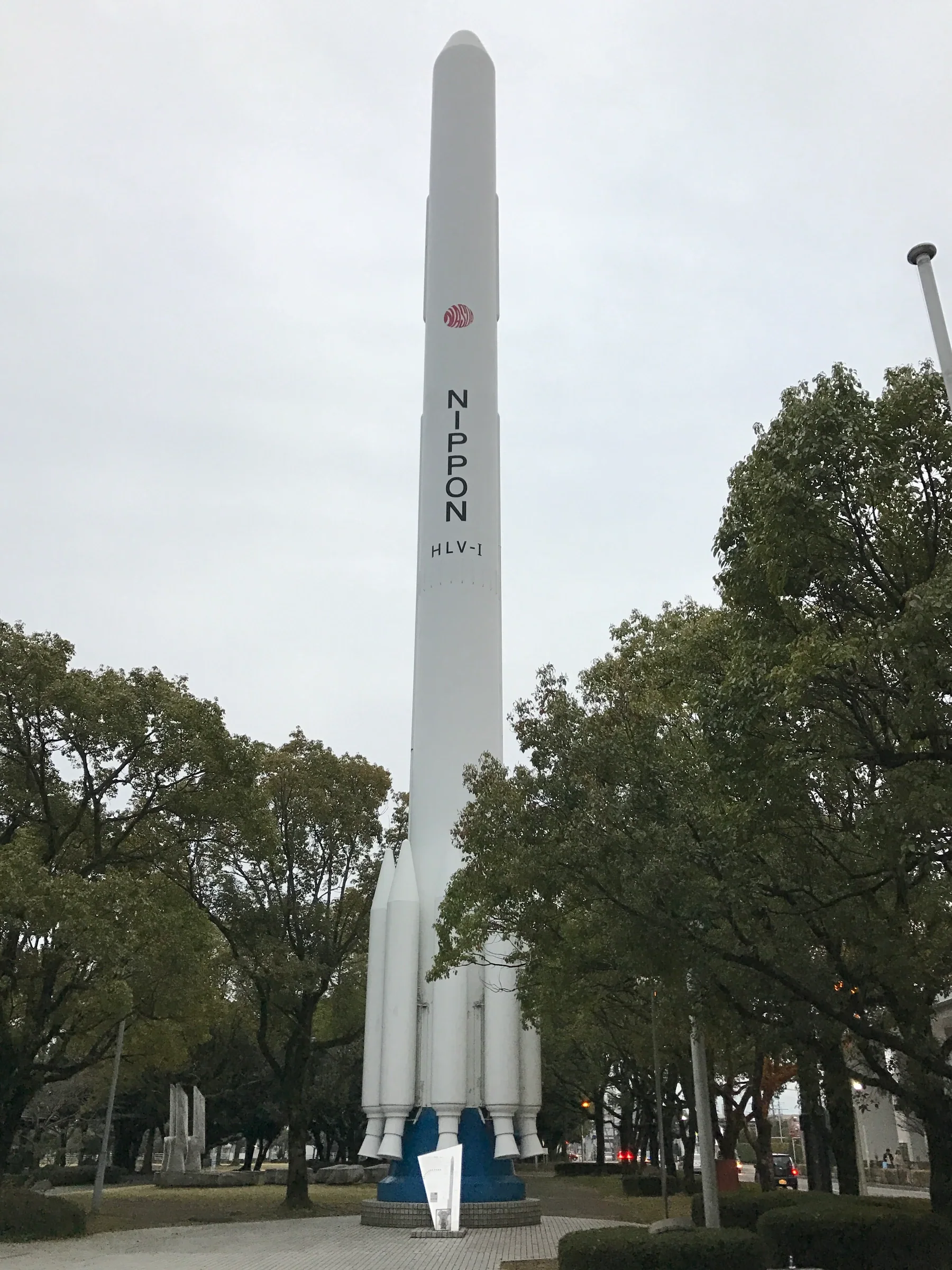 宮崎科學技術館旁的 H-I 火箭實物大小模型，火箭主體從樹間升起