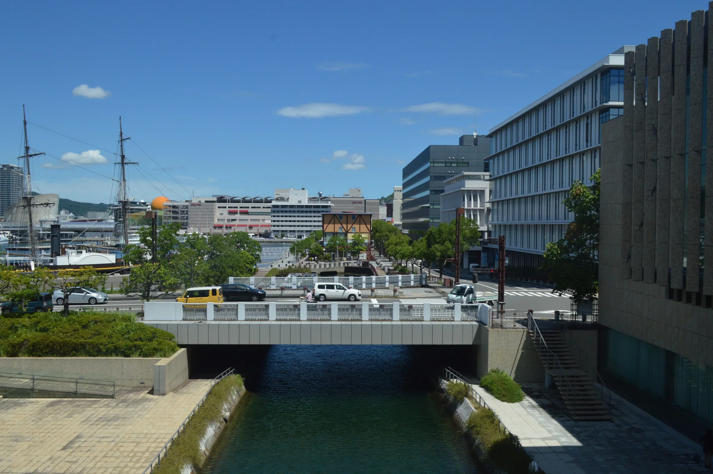 從長崎縣美術館的回廊望向港區建築和下方運河，館舍格柵沿右側延伸
