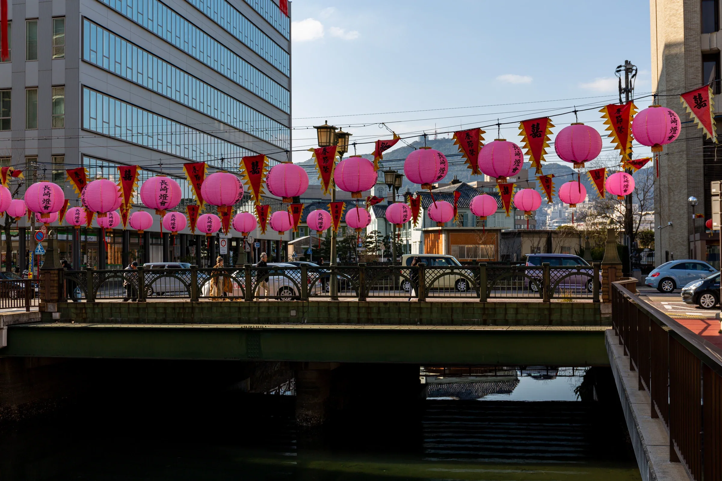 2019 年銅座川橋上懸掛粉紅色長崎燈籠,河道與市區建築在日光下可見