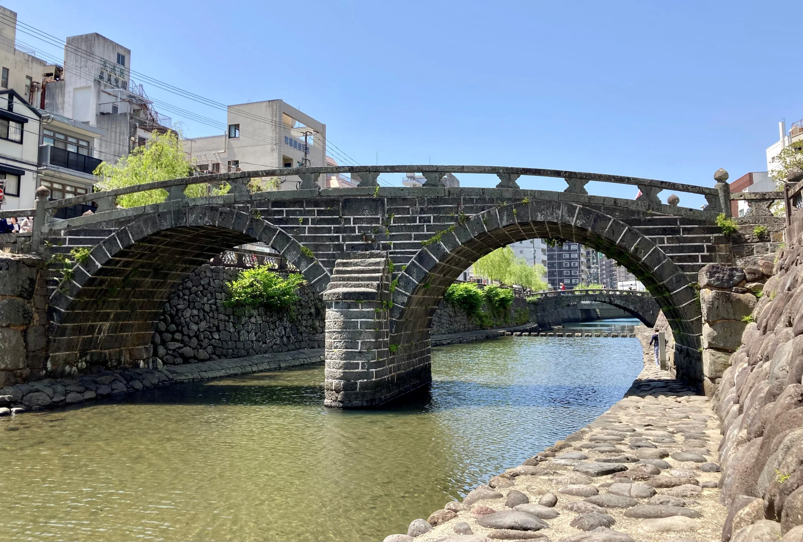 晴天時的長崎眼鏡橋橫跨中島川,兩道石拱與河岸同框