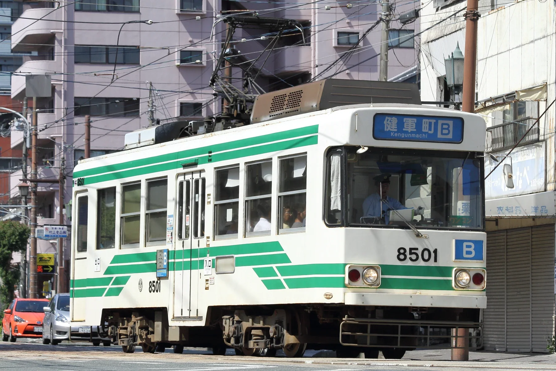 熊本市電 8501 號行駛在市中心街道，通町筋是前往 OMO5 熊本的下車站