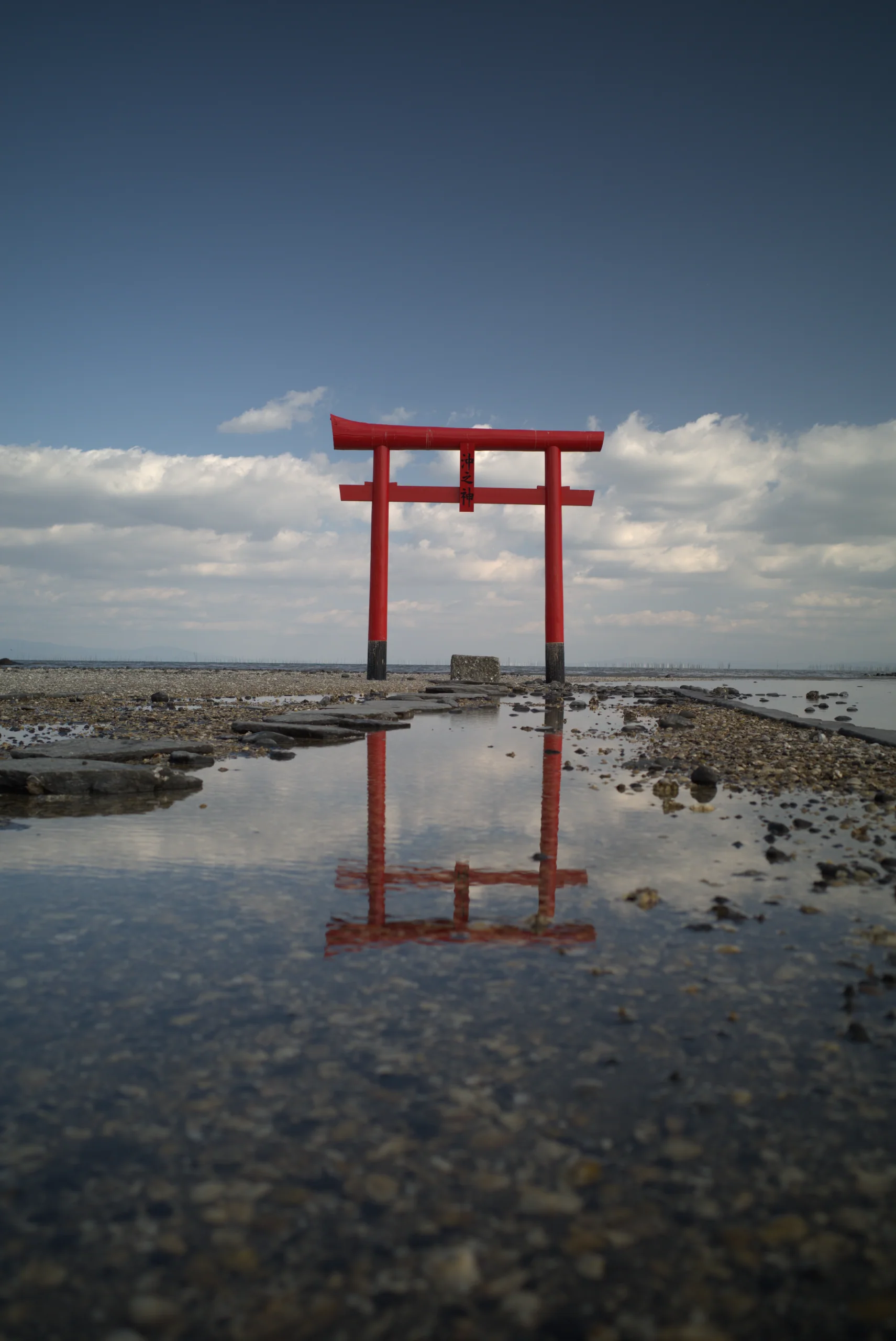 退潮的有明海上,三座朱紅色海中鳥居立在潮灘中,水面映出倒影