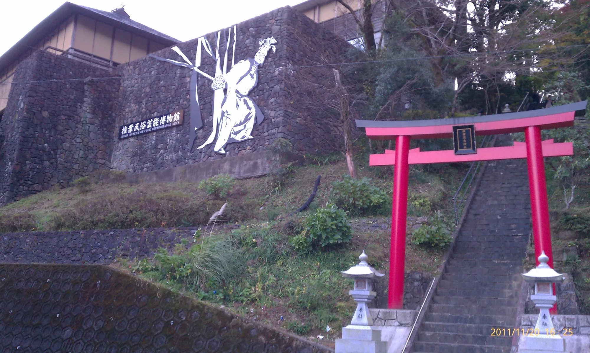 椎葉民俗藝能博物館外牆、階梯與旁側鳥居，位於山坡聚落中