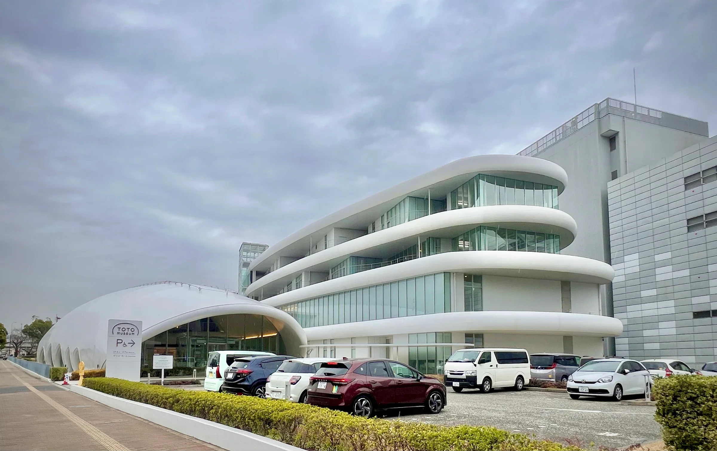 2026年2月TOTO Museum白色曲線館舍與前方停車區,非特展展場