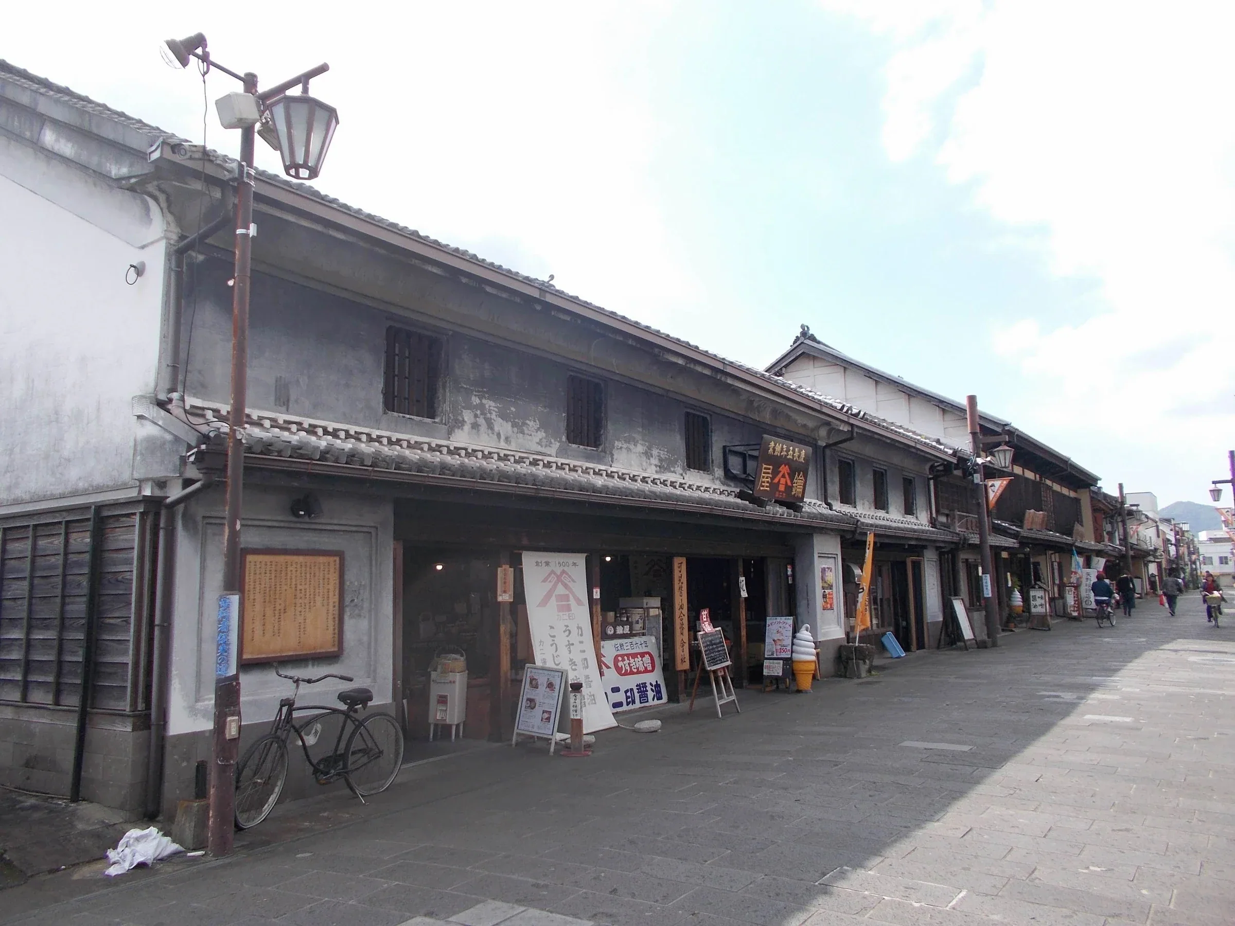 臼杵八町大路白天街景，老店屋沿石板路排列，街道向遠處延伸