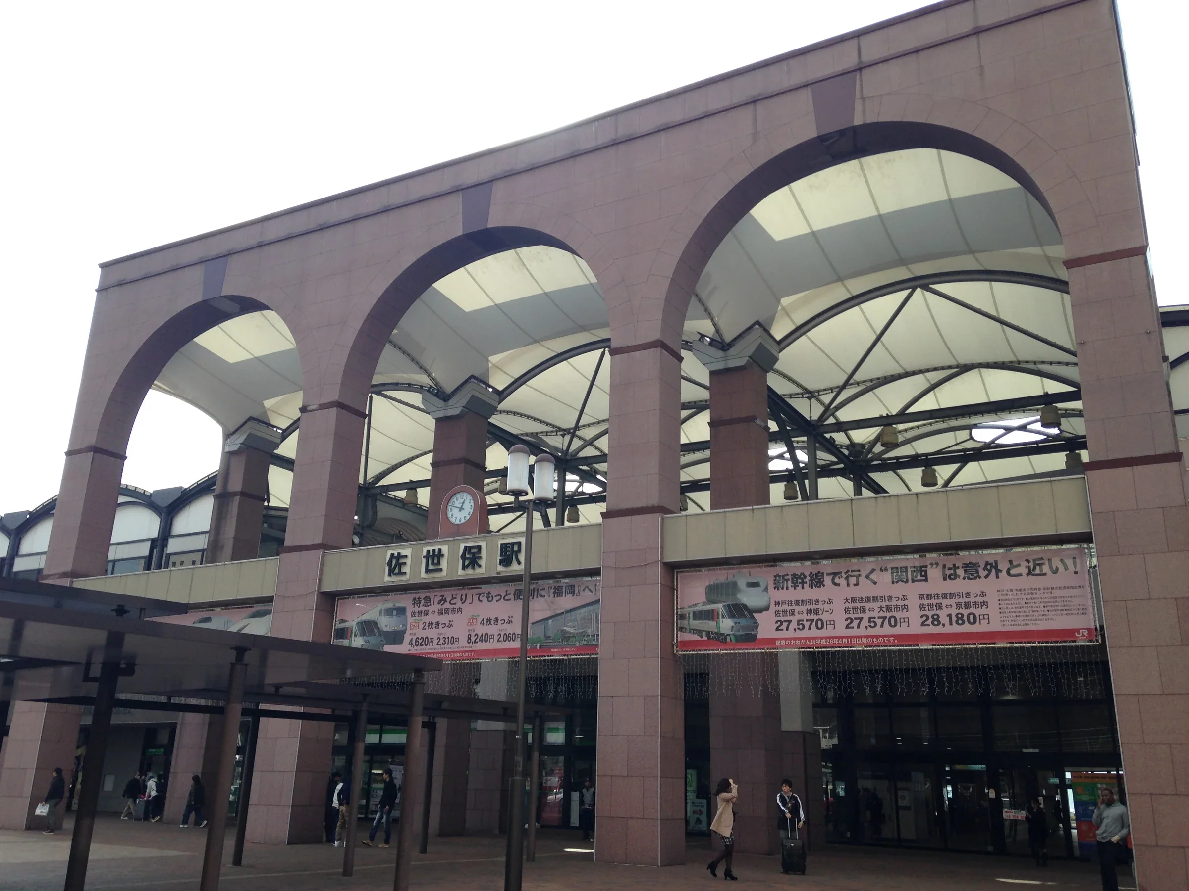 佐世保站東口外觀與站前人行道，入口招牌位在大型拱形屋頂下